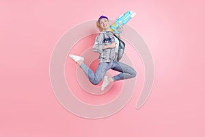 Full size photo of funky blond millennial lady play watergun wear jeans jacket visor isolated on pink background