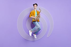 Full size photo of funky brunet millennial guy jump with sax wear shirt jeans isolated on violet color background