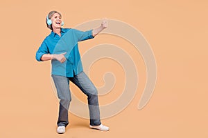 Full size photo of funky crazy retired woman dressed stylish shirt in headphones play imaginary guitar isolated on