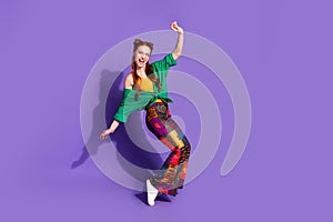 Full size photo of funny adorable woman dressed green shirt vintage pants stand on tiptoes dancing isolated on purple