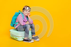 Full size photo of funny relaxing boy sitting on baggage go on adventure trip isolated on yellow color background