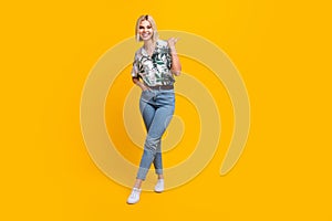 Full size photo of gorgeous girl wear print shirt denim pants indicating at proposition empty space isolated on yellow