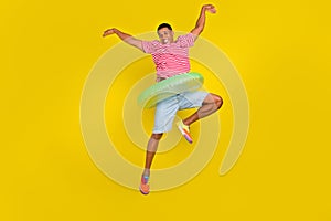 Full size photo of guy jump like ballerina hold ring swimmer wear shorts shirt isolated over yellow color background