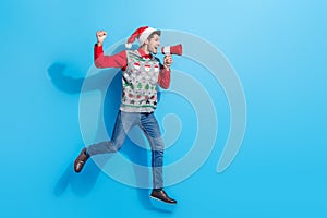 Full size photo of handsome young guy run raise fist megaphone dressed x-mas print vest hat outfit isolated on blue