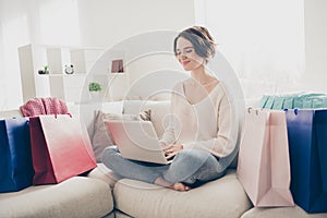 Full size photo of happy charming bob haired woman sit sofa hold look laptop shopper indoors in home living-room
