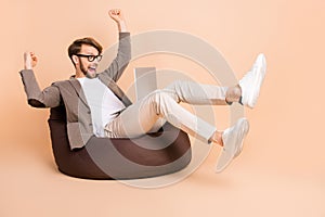 Full size photo of happy excited crazy businessman in glasses raise fists in victory use laptop isolated on beige color