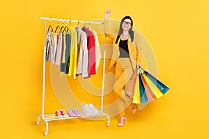 Full size photo of hooray young lady hold bags near garderobe wear eyewear yellow suit isolated on vivid color