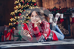 Full size photo of lovely peaceful girl laying floor use smart phone newyear tree lights decor giftbox flat indoors
