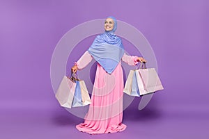 Full size photo of lovely young lady with shoppers look ramadan holiday wearing blue hijab muslim pink dress isolated