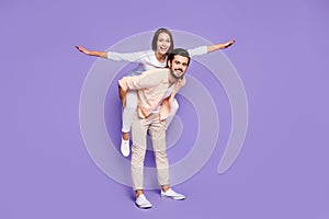 Full size photo of married couple piggyback have fun weekend hands wings fly isolated on purple color background