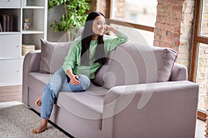 Full size photo of nice content korean girl sit comfy divan look window in house indoors