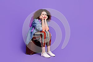 Full size photo of nice girl disappointed sit valise wear denim shirt isolated on violet color background