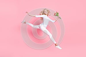 Full size photo of nice happy young woman jump up flexible hold flowers isolated on pink color background