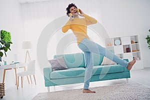 Full size photo of nice young man headphones dance wear yellow pullover white interior apartment indoors