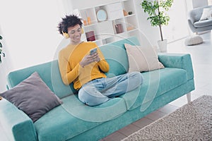 Full size photo of nice young man headphones smart phone wear yellow pullover white interior apartment indoors