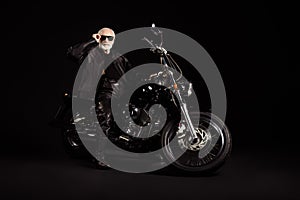 Full size photo of old man confident cool biker man sit bike touch sunglasses specs wear modern outfit isolated over
