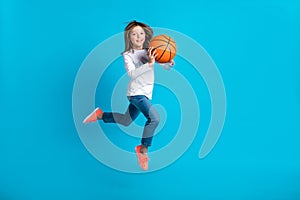 Full size photo of optimistic active girl wear white long sleeve trousers running with basketball ball isolated on blue