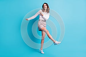 Full size photo of optimistic cool brunette girl stand dance wear shirt skirt sneakers  on teal background