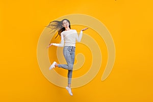 Full size photo of optimistic girl jump wear sweater jeans sneakers isolated on yellow color background