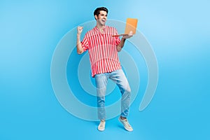 Full size photo of overjoyed ecstatic man dressed striped shirt denim pants hold laptop win lottery yell isolated on