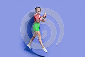 Full size photo of overjoyed woman flying with smartphone in hands impressed by fast intenet connection isolated on blue