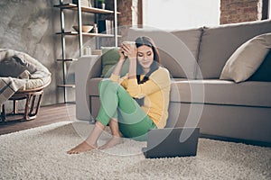 Full size photo of positive cheerful girl sit carpet barefoot use computer watch interesting movie hold cup with hot
