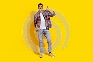 Full size photo of satisfied man dressed plaid shirt jeans trousers showing thumb up approve nice job isolated on yellow