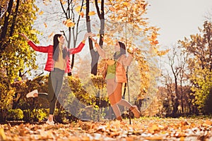 Full size photo of two girls buddies people enjoy fall park weekend free time throw catch air fly maple leaves wear red