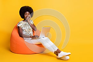 Full size photo of young african excited amazed happy girl woman sit armchair work computer isolated on yellow color