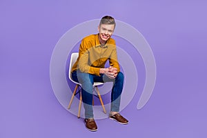 Full size photo of young cheeerful man sit stool stand-up tv show wear modern outfit isolated over violet color