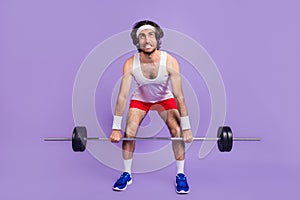 Full size photo of young crazy man in glasses look copyspace trying to lift heave barbell isolated on violet color