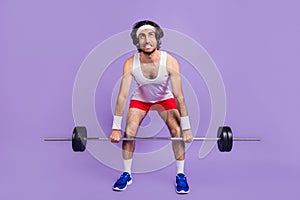 Full size photo of young crazy man in glasses look copyspace trying to lift heave barbell isolated on violet color photo