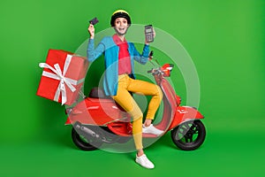 Full size photo of young excited girl in yellow helmet deliver red gift hold credit card terminal  on green