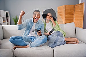 Full size photo of young man girl sit sofa play videogame playstation winner loser interior indoors cozy daylight