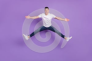 Full size photo of young man happy positive smile active energetic jump split isolated over violet color background