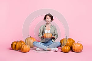 Full size photo of young pretty girl sit floor hold pumpkin impressed many veggies isolated over pink color background