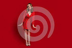 Full size portrait of elegant lovely girl mini dress stilettos posing empty space ad isolated on red color background