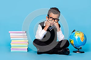 Full size portrait of minded intelligent boy sitting floor look empty space isolated on blue color background