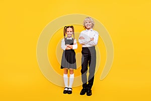 Full size portrait of two satisfied school persons folded hands look camera isolated on yellow color background