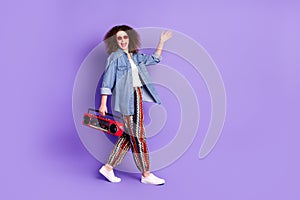 Full size profile photo of cool nice girl hold boombox wave hi walk empty space wear denim shirt isolated on violet