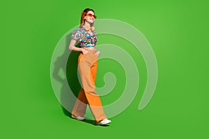 Full size profile photo of pretty young woman walk empty space wear top isolated on bright green color background