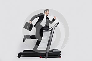 Full size profile portrait of elegant sporty manager hold briefcase run fast treadmill empty space isolated on grey