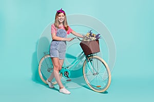 Full size profile portrait of lovely girl bike basket wildflowers isolated on cyan color background