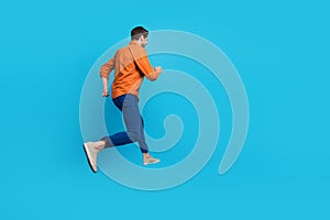 Full size profile rear portrait of energetic crazy young man jumping running empty space advert isolated on blue color