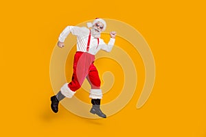 Full size profile side photo of funky crazy fairy grey hair beard santa claus hipster in red hat jump go run winter time