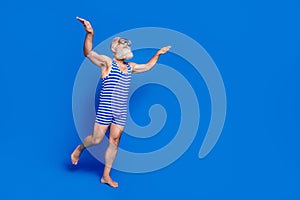 Full size profile side photo of funky funny old man in goggles diving in swimming pool isolated on blue color background
