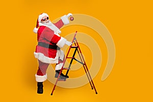 Full size profile side photo of funky funny santa claus decorate christmas tree climb stairs want hang x-mas ornament on