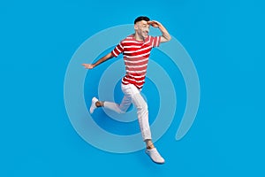 Full size profile side photo of handsome brunette man look froward copyspace run jump isolated on blue color background