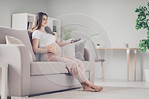 Full size profile side photo of young beautiful happy smiling positive pregnant woman sit sofa watching tv at home house