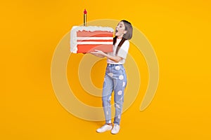 Full size profile side photo of young excited woman bite cake birthday party isolated over yellow color background